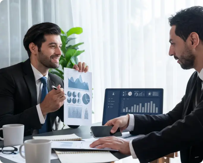 male showing graphs to another male using computer