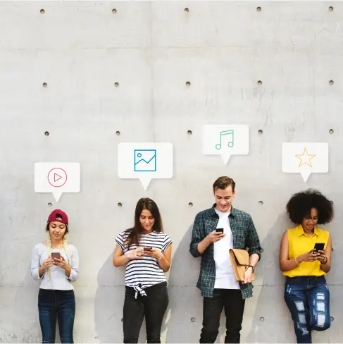 team of four leaning on wall and using their phones