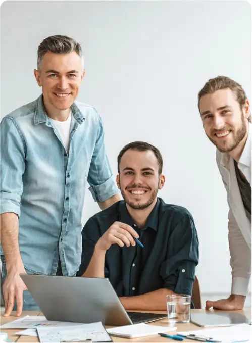 three middle aged men behind computer looking in this direction